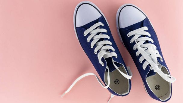 μπλε αθλητικά παπούτσια με κορδόνια σε ροζ φόντο, μονωτικά - Φωτογραφία, εικόνα