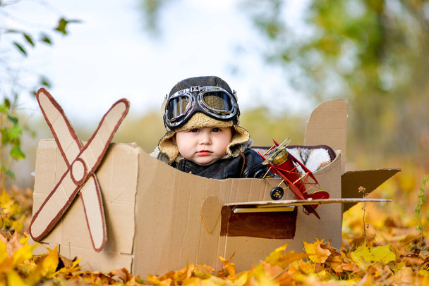 Πολύ χαριτωμένο αγόρι που κάθεται σε αεροπλάνο από χαρτόνι, μελλοντικός πιλότος, επάγγελμα όνειρο ζωής - Φωτογραφία, εικόνα