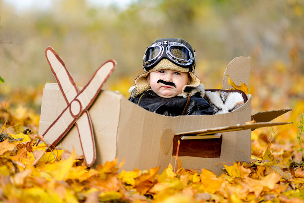Очень симпатичный мальчик, сидящий в картонном самолете, будущий пилот, профессия пожизненной мечты - Фото, изображение