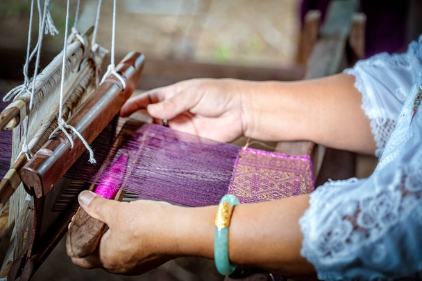 Tissage traditionnel de soie Isan Thai. vieille femme tissage à la main de la soie de manière traditionnelle au métier à tisser manuel. Thaïlande. Concentration sélective. - Photo, image
