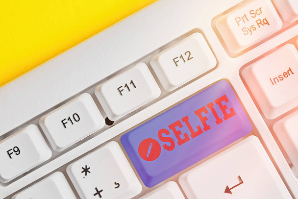 Conceptual hand writing showing Selfie. Business photo showcasing taken by oneself using a digital camera for posting on social network White pc keyboard with note paper above white key copy space. - Photo, Image