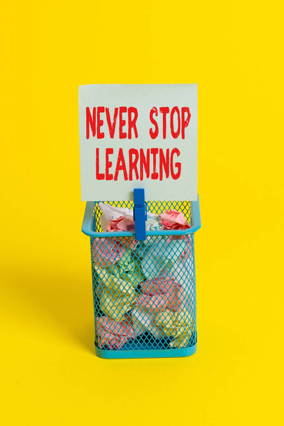 Conceptual hand writing showing Never Stop Learning. Business photo text continuous education and techniques to be competitive Trash bin crumpled paper clothespin office supplies yellow. - Photo, Image