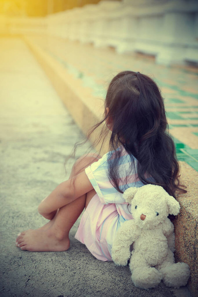 Um ursinho sentado ao lado de uma menina asiática sozinho. Esperando que a mãe volte para casa com espaço de cópia
. - Foto, Imagem