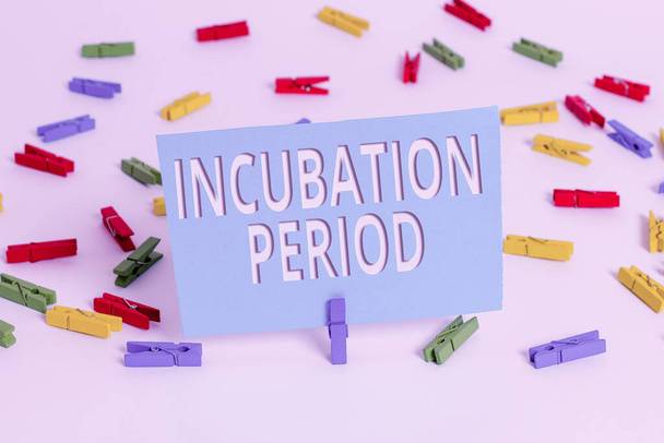 Text sign showing Incubation Period. Conceptual photo time elapsed starting from getting exposed to an infectious agent Colored clothespin papers empty reminder white floor background office. - Photo, Image