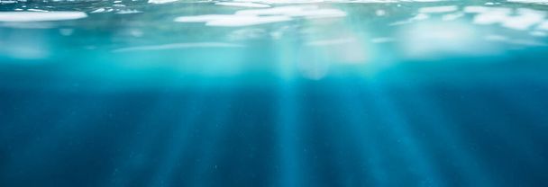 Blauw onderwater met zonlicht dat schijnt door het wateroppervlak in tropische zee achtergrond - Foto, afbeelding