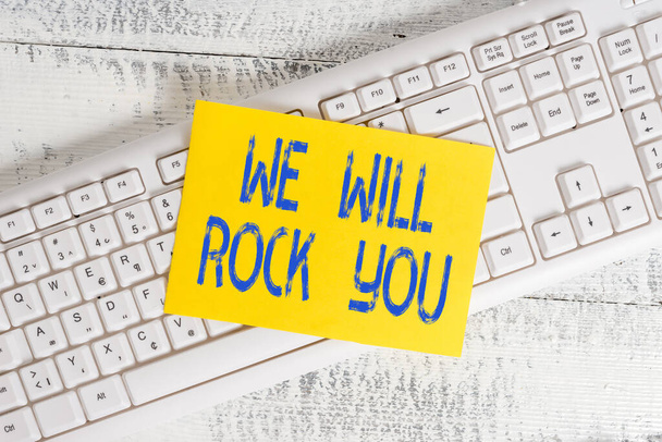 Tekst pisma "We Will Rock You". Koncepcja oznaczająca wyjście i zwrócenie się w stronę świata i wszystkiego, co w nim jest Białe biuro klawiatury dostarcza puste prostokąty w kształcie papieru przypominającego drewno. - Zdjęcie, obraz