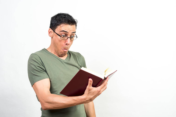 Az ember olyasmit olvas, ami nagyon meglepi egy könyvben. Közepes lövés. Fehér háttér. - Fotó, kép