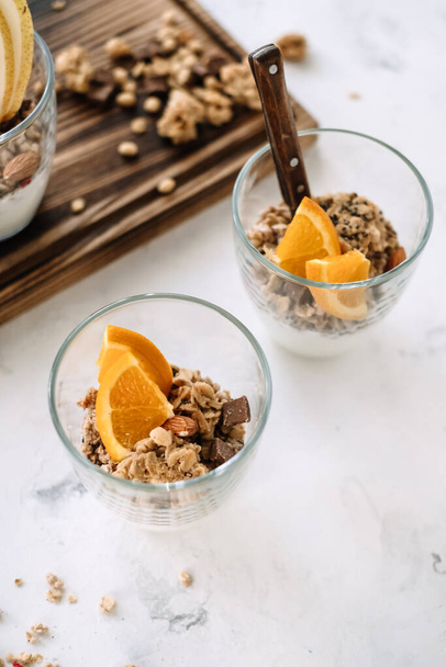 Muesli and natural yogurt with slices of fruits and nuts in a glass cup - 写真・画像