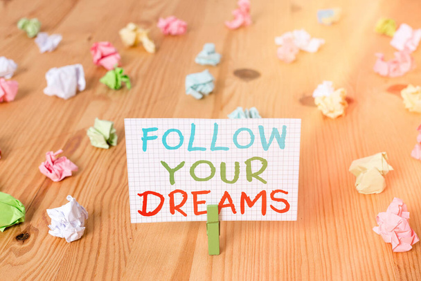 Fogalmi kézírás a Follow Your Dreams-ről. Üzleti fotó bemutató motivációs és inspiráló kifejezés, hogy folytassa a szív vágy színes gyűrött papírok fa padló háttér - Fotó, kép
