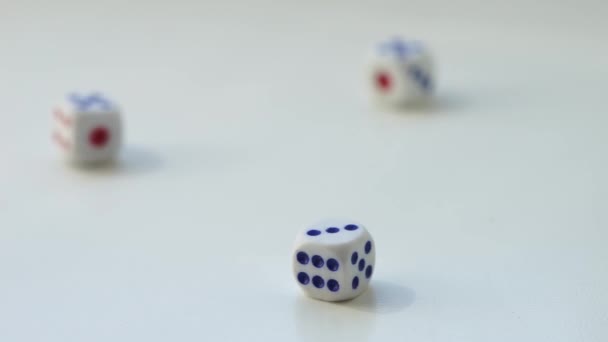 Τρία ζάρια πέφτουν σε ένα λευκό τραπέζι με διαφορετικούς αριθμούς. Πλευρική άποψη, επιλεκτική εστίαση - Πλάνα, βίντεο