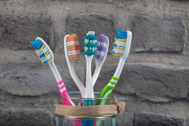 Kleurrijke tandenborstels in glas op blauwe houten ondergrond. Tandheelkundige en mondverzorging. - Foto, afbeelding