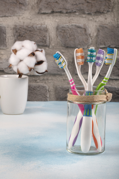 Cepillos de dientes coloridos en vidrio sobre fondo de madera azul. Concepto de cuidado dental y oral
. - Foto, imagen