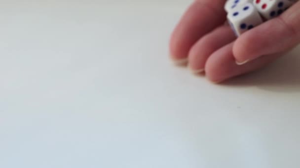 Primer plano mano tirando dados en una mesa blanca con diferentes números. Vista lateral
 - Metraje, vídeo