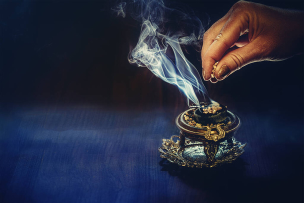 incenso na mão de uma mulher, fumaça de incenso em um fundo preto - Foto, Imagem