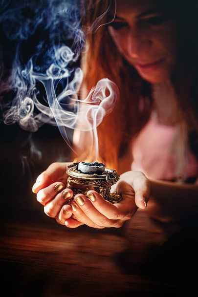 incense in a woman hand, incense smoke on a black background - Фото, зображення