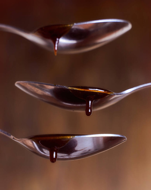 Honey in a spoon.White background - Φωτογραφία, εικόνα