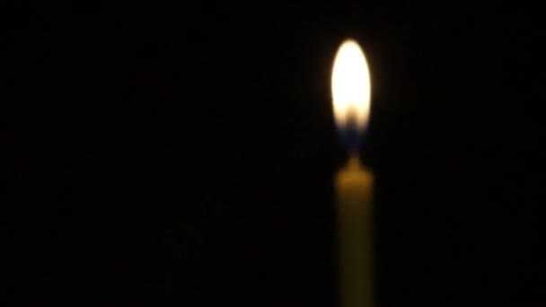 Unscharfe Kerze brennt im dunklen schwarzen Raum - Filmmaterial, Video