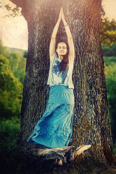 junge Frau praktiziert Yoga am Baum. - Foto, Bild