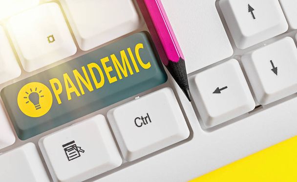 Word writing text Pandemic. Business concept for occurring over a wide area affecting high proportion of population White pc keyboard with empty note paper above white key copy space. - Photo, Image