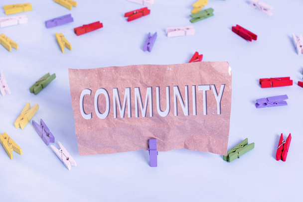 Text sign showing Community. Conceptual photo group of showing with a common characteristics living together Colored clothespin papers empty reminder blue floor background office pin. - Photo, Image