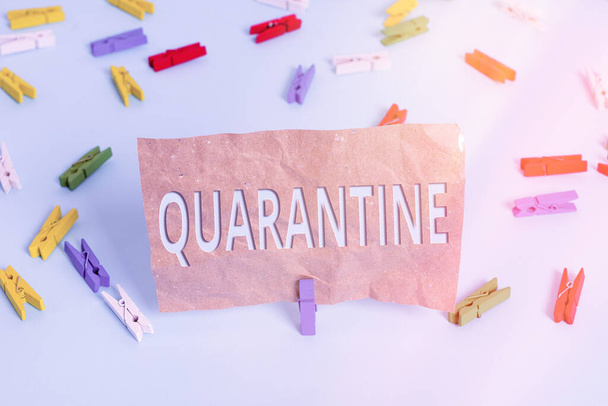 Text sign showing Quarantine. Conceptual photo restraint upon the activities of an individual or the transport of goods Colored clothespin papers empty reminder blue floor background office pin. - 写真・画像