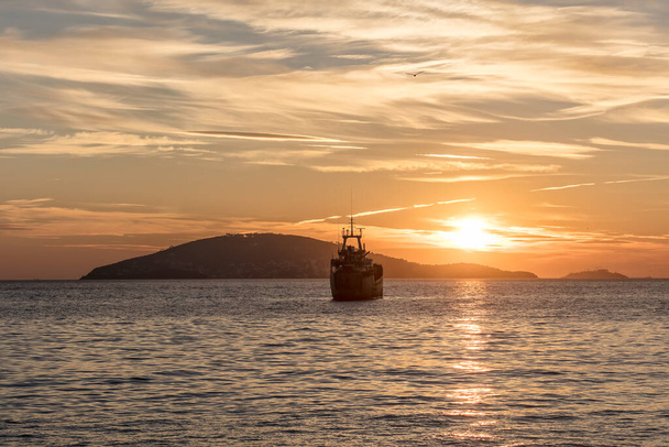 θέα πλοίου που πλέει στον ορίζοντα κατά τη διάρκεια του ηλιοβασιλέματος - Φωτογραφία, εικόνα