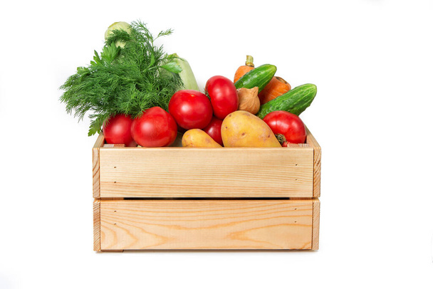 Wooden box with vegetables on a white background. Zucchini, carrots, tomatoes, cucumbers and greens. Fresh vegetables. Agricultural Products. - Foto, Bild
