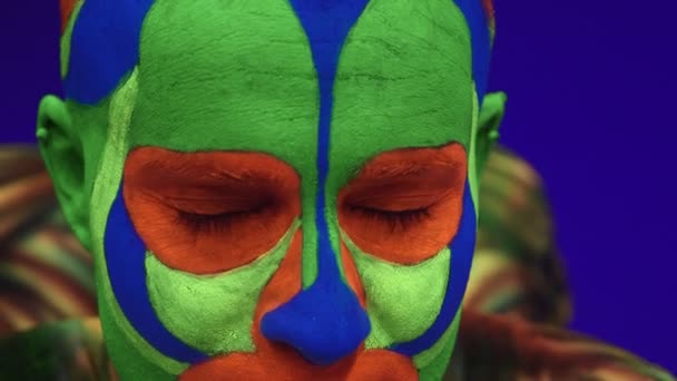 Acrobatic twins in neon costumesto perform a stand on the hands and head,on blue cyclorama in ultraviolet makeup in an alien style.Bright fluorescent body art glows in darkness. - Footage, Video
