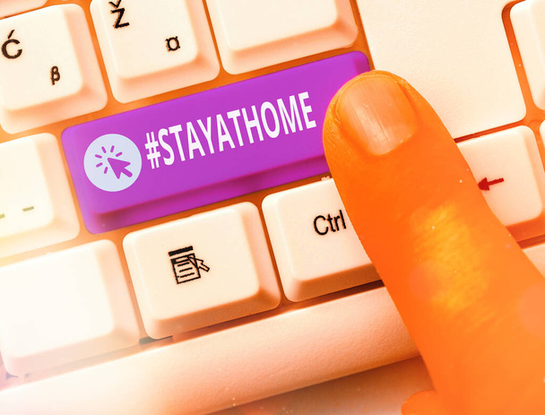 Konzeptionelle Handschrift mit dem Hashtag Stay at home. Geschäftsfoto, das ein Trendetikett in den sozialen Medien im Zusammenhang mit dem Coronvirus-Ausbruch zeigt Weiße PC-Tastatur mit Notizpapier über weißer Taste - Foto, Bild