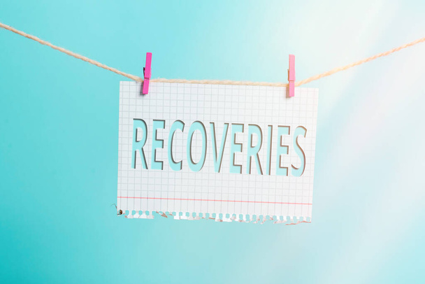 Text sign showing Recoveries. Conceptual photo process of regaining possession or control of something lost Clothesline clothespin rectangle shaped paper reminder white wood desk. - Photo, Image