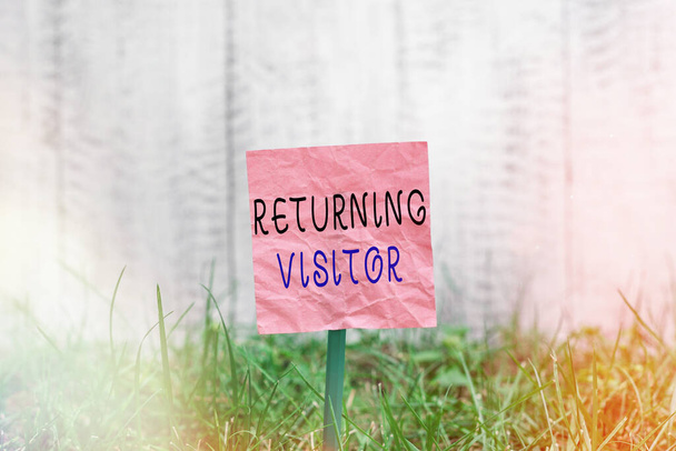 Conceptual hand writing showing Returning Visitor. Business photo text who had visited before and come back to your site Plain paper attached to stick and placed in the grassy land. - Photo, Image