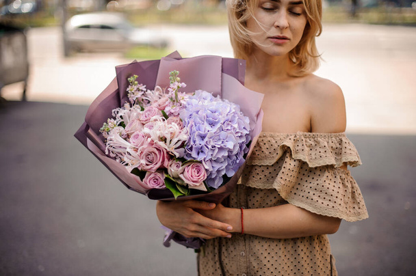 młoda kobieta posiada delikatny bukiet hortensji i róż. - Zdjęcie, obraz