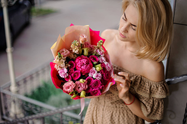 young beautiful woman holds bouquet with bright bouquet of fresh roses and other flowers - Foto, imagen