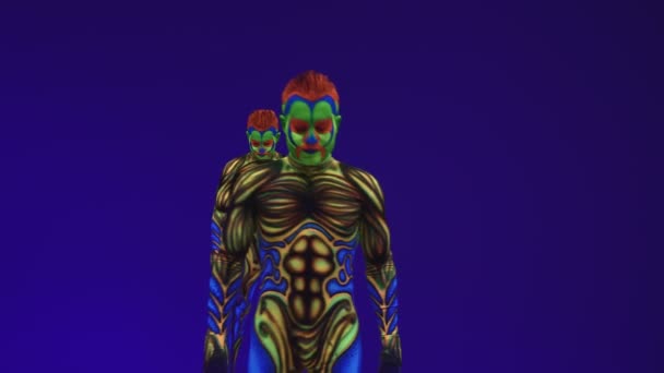 Gêmeos acrobáticos em trajes de néon para realizar um suporte nas mãos e na cabeça, no cyclorama azul na composição ultravioleta em um estilo alienígena.Arte corporal fluorescente brilhante brilha na escuridão
. - Filmagem, Vídeo