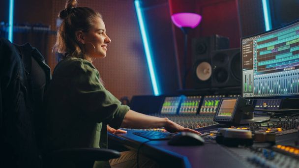 Beautiful, Stylish Female Audio Engineer and Producer Working in Music Recording Studio, Uses Mixing Board and Software to Create Cool Song. Creative Girl Artist Musician Working to Produce New Song - Foto, immagini