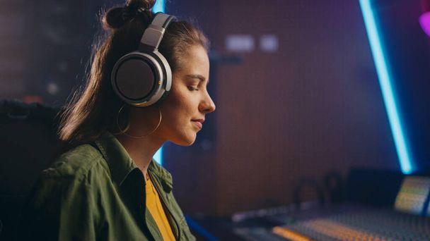 Portrét krásné ženské umělkyně hudebnice v hudebním nahrávacím studiu používá sluchátka, mixážní prkno Vytvořit moderní píseň. Úspěšný ženský zvukový inženýr, producent. - Fotografie, Obrázek
