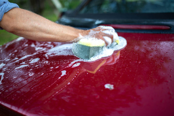 赤い車を手で洗い車の後ろに泡のついたフック. - 写真・画像