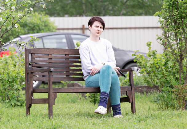 A girl in home clothes sitting on a bench with a smartphone in her hand - Photo, Image