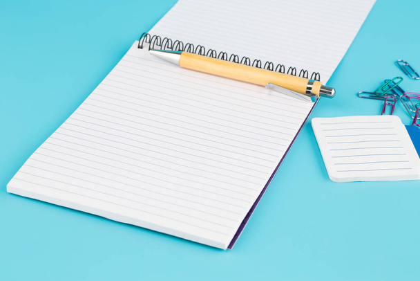 Notepads, pen and paper clips on blue background. - Zdjęcie, obraz