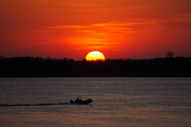 Big Sun and Fisherman in an inflatable boat - Фото, зображення