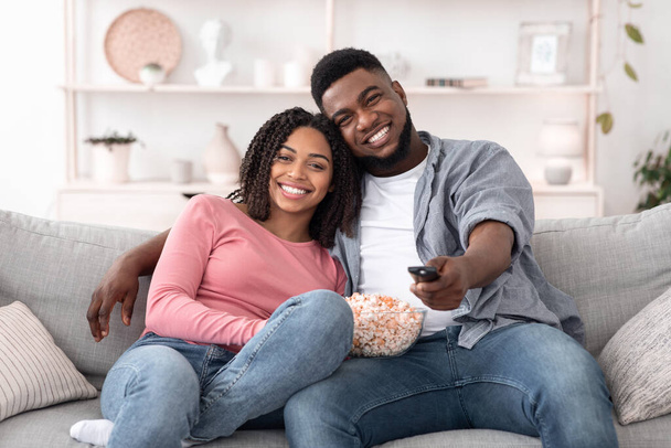 Романтическая чёрная пара с попкорном смотрит телевизор дома
 - Фото, изображение
