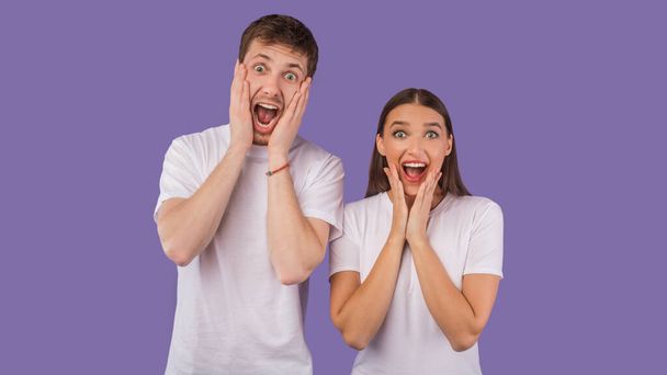 Excited young couple screaming happily at camera at studio - 写真・画像