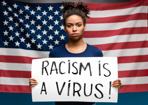 Afrikaanse vrouw staande met poster Racisme is een virus - Foto, afbeelding
