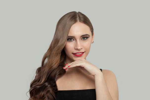 Lovely young woman with red lips makeup and long brown curly hair portrait - Fotó, kép