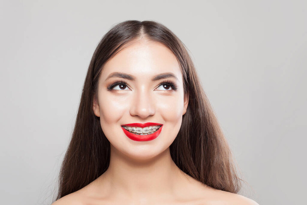 Vrolijke vrouw met beugels op tanden op wit, mooi vrouwelijk gezicht close-up - Foto, afbeelding