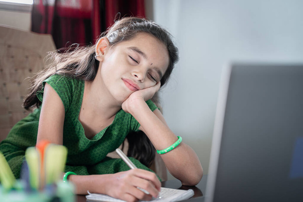 Enfant fille dormant pendant la classe en ligne devant l'ordinateur portable concept d'enfant fatigué de l'enseignement à distance ou de l'éducation en ligne à la maison pendant le verrouillage covid-19 ou coronavirus - Photo, image