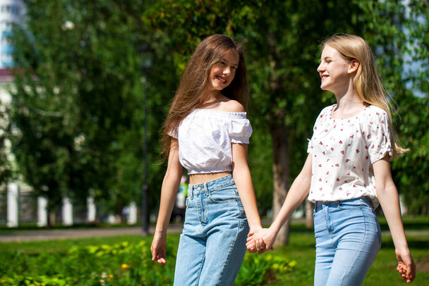 Two funny girlfriends teenagers are walking in the summer park. - Foto, Imagen