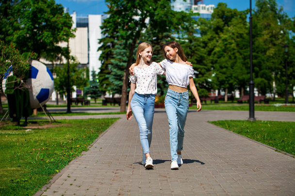 Two funny girlfriends teenagers are walking in the summer park. - Foto, Bild