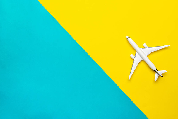 Vliegtuigreisconcept. Wit speelgoedvliegtuig, vliegtuig op helderblauw en geel. Lucht lucht vliegen achtergrond. - Foto, afbeelding