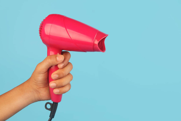 Mão segurando um novo secador de cabelo cor de rosa - Foto, Imagem